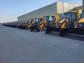 Backhoe loaders stand in a line.