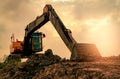 Backhoe parked at construction site after digging soil. Bulldozer on sunset sky and clouds background. Digger after work. Earth Royalty Free Stock Photo