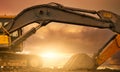 Backhoe parked at construction site after digging soil. Bulldozer on sunset sky and clouds background. Digger after work. Earth Royalty Free Stock Photo