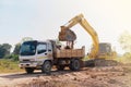 Backhoe scoop the soil load to truck in a middle day Royalty Free Stock Photo
