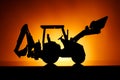Backhoe tractor silhouette, orange sunset background