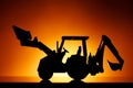 Backhoe tractor silhouette, orange background