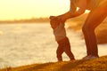 Confident baby learning to walk and mom helping him