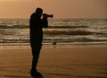 Backlight silhouette of photographer standing upon the foreshore Royalty Free Stock Photo