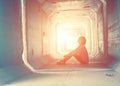 Backlight of a teenager depressed sitting inside a dirty tunnel Royalty Free Stock Photo