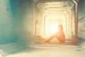 Backlight of a teenager depressed sitting inside a dirty tunnel Royalty Free Stock Photo