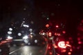 backlights and frontlights at night on a road, view trough windshield with raindrops on it Royalty Free Stock Photo