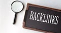 BACKLINKS - word in electronic notebook on white background with magnifying glass Royalty Free Stock Photo