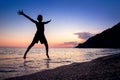 Backlit boy silhouette jumping with joy over the water on a beach. Royalty Free Stock Photo