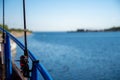 A backlit closeup picture of a blue rail and a fishing rod on a boat. Background with a clear blue sky and blue ocean Royalty Free Stock Photo