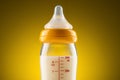 Backlit glass baby bottle with powdered milk closeup