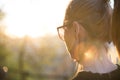 Backlit rear view of young woman talking on cell phone outdoors in park at sunset. Girl holding mobile phone, using Royalty Free Stock Photo