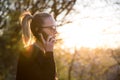 Backlit rear view of young woman talking on cell phone outdoors in park at sunset. Girl holding mobile phone, using Royalty Free Stock Photo