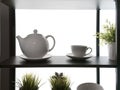 Backlit shelf fragment with kitchenware silhouettes. teapot kettle pot plant on the wooden shelf white wall kitchen Royalty Free Stock Photo