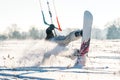 Backlit shot of Snowkiter doing a butter slide trick in fresh powder on a sunny day