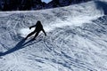 Backlit silhouette of man in action practicing ski going fast and aggressive down snow slope winter sport