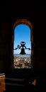 Backlit silhouette of restored bronze bell of the Torre de la Clerecia with evening sunlight streaming through the arched window