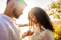 Backlit suggestive romance scene of young beautiful multiracial couple in love. Handsome guy making the marriage proposal to her