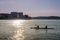 Backlit sunset view of a couple canoeing in the city.