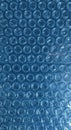 Backlit texture of clear plastic bubble wrap packaging material with a repeating circular pattern and blue hue, offering a Royalty Free Stock Photo