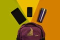 Backpack with accessories, tablet computer, phone and a thermo mug on a bright background, yellow green orange. Outfit of student,