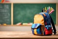 Backpack bag and school supplies on the wooden table, blurred background. Royalty Free Stock Photo