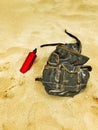 Backpack and canteen water bottle in the sand of a beach.