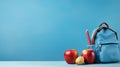 Backpack with different colorful stationery and apple on table and blue background. Banner design back to school concept Royalty Free Stock Photo