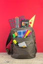 Backpack with different colorful stationery on table. Bright Red background. Back to school Royalty Free Stock Photo