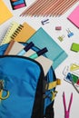 Backpack with different school stationery on white background, flat lay Royalty Free Stock Photo