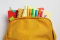 Backpack with different school stationery on white background, top view Royalty Free Stock Photo