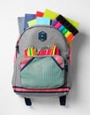 Backpack with different school stationery on white background, top view Royalty Free Stock Photo