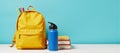 Backpack full of school supplies books pens on table accompanied by a blue water bottle backtoschool theme