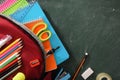 Backpack full of school supplies on green blackboard detail top Royalty Free Stock Photo