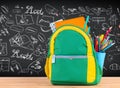 Backpack full of school supplies over black school board background Royalty Free Stock Photo