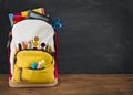 Backpack full of school supplies over black school board background Royalty Free Stock Photo