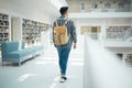 Backpack, library and education with a man student walking in a university bookstore for learning or development. Back