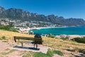 Backpack of lonely traveller on a bench with a view of Camps bay beautiful beach in Cape Town