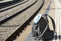 A backpack with a n95 face mask attached on it, on a train station platform with rails in the background, transport at coronavirus Royalty Free Stock Photo