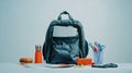 A backpack filled with notebooks and school supplies on a white table against a light blue wall Royalty Free Stock Photo