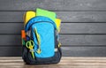 Backpack with school stationery on table against grey wooden background