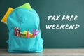 Backpack with school stationery and text TAX FREE WEEKEND written on chalkboard Royalty Free Stock Photo