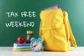 Backpack with school stationery and text TAX FREE WEEKEND written on chalkboard Royalty Free Stock Photo