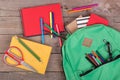 Backpack and school supplies books, pencils, notepad, felt-tip pens, eyeglasses, scissors on brown wooden table Royalty Free Stock Photo