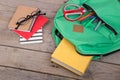 Backpack and school supplies books, pencils, notepad, felt-tip pens, eyeglasses, scissors on brown wooden table Royalty Free Stock Photo