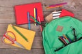 Backpack and school supplies: books, pencils, note pad, felt-tip pens, eyeglasses, scissors on brown wooden table Royalty Free Stock Photo