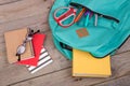 Backpack and school supplies: books, pencils, notepad, felt-tip pens, eyeglasses, scissors on wooden table Royalty Free Stock Photo