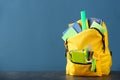 Backpack with school supplies on grey table against color background