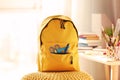 Backpack with school supplies on pouf Royalty Free Stock Photo