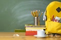 Backpack, textbooks, stationery and school supplies on wooden desk